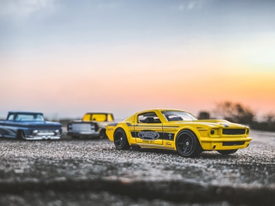 During the day, yellow and black Chevrolet camaro in grey driving on the beach
